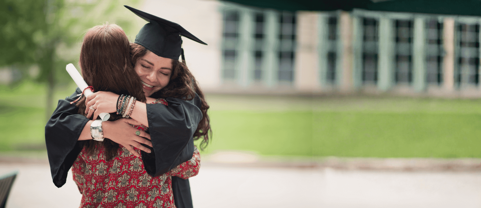 Joven celebrando su graduación con un abrazo, simbolizando el cumplimiento de metas a largo plazo y la tranquilidad financiera.