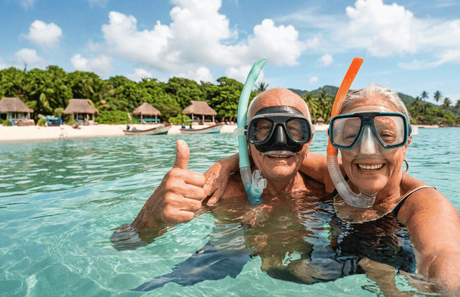 Pareja disfrutando de un retiro envidiable haciendo esnórquel en el mar, reflejando los beneficios de un seguro de vida con ahorro e inversión.