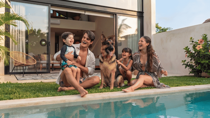 Familia sonriente disfrutando junto a la alberca y su mascota, reflejando los beneficios a largo plazo de un seguro de vida con inversión en México.